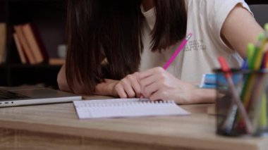 Kadın öğrenci dizüstü bilgisayardaki akademik makaleyi okurken not alıyor. Solak kadın kütüphanede oturan not defterine notlar kaydetti.