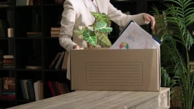 Kadın yönetici, ofisteki masasından kişisel eşyalarının olduğu ağır bir kutu alır. Kadın çalışan, modern şirketteki işi bırakarak erzak alıyor.