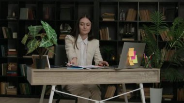 Mutlu kadın ofis çalışanı ofisteki sandalyeye kağıtları fırlatıyor. Takım elbiseli neşeli bayan çalışan başarılı iş anlaşmasını kutluyor