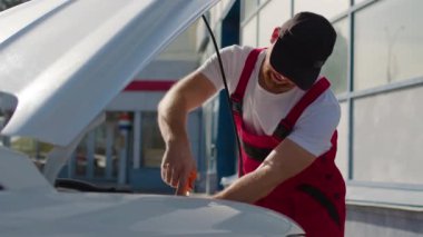 Profesyonel, araba motorunu tamir etmek için özel bir alet kullanır. Araç servisi çalışanı, otomobilin işlevselliğini otomobil servis istasyonunun yakınındaki çalışma alanında geri kazandırıyor