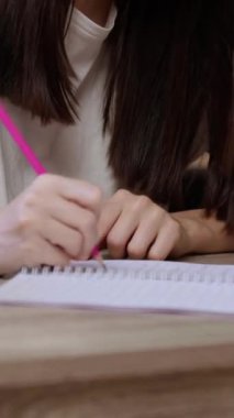 Genç kadın üniversite kütüphanesindeki akademik materyalleri not alıyor. Bayan öğrenci, dizüstü bilgisayardan bilgi okuyarak üniversitede not defteri yazıyor.