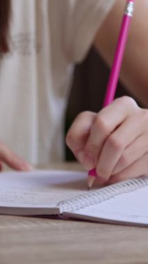 Kadın öğrenci, tahta masada oturan kalemle deftere yazıyor. Solak kadın üniversitede dizüstü bilgisayardaki notları gözden geçiriyor.