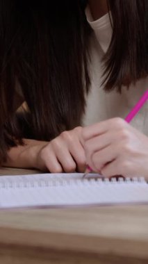 Kadın öğrenci dizüstü bilgisayardaki akademik makaleyi okurken not alıyor. Solak kadın kütüphanede oturan not defterine notlar kaydetti.