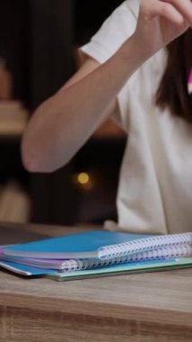 Genç kız öğrenci kütüphanede deftere not almak için kalem alır. Esmer kadın, okuma odasında laptopta online materyalleri inceliyor.