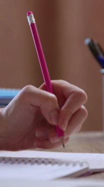 Kadın öğrenci sol elini not defterine temel akademik taslakları yazıyor. Kadın, okuma odasında oturan kalemle eğitici sezgileri kaydediyor.