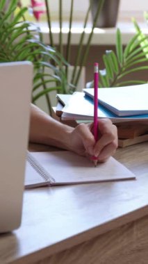 Kadın öğrenci dizüstü bilgisayarda akademik makale okurken notlar yazıyor. Esmer kadın kayıtları üniversitede masadaki ana notlarda ders veriyor.