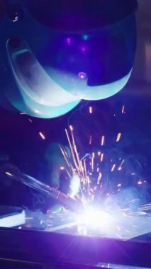 Deneyimli nalbant fabrika atölyesinde çelik kaplama üzerine çalışıyor. Loş aydınlatılmış dükkanda hassas metal işleme süreci