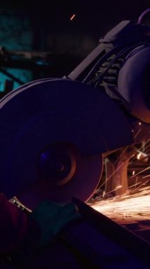 Profesyonel nalbant, dükkanın kapanmasında kıvılcımlar çıkaran elektrikli testereyle metal çubukları kesiyor. Çalışan çelik profil üzerinde çalışıyor.