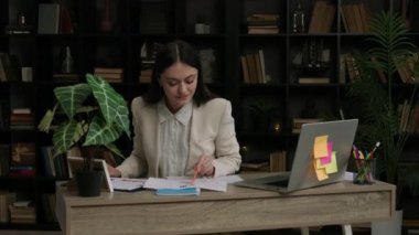 Neşeli ve neşeli bir ofis kadını bugün için belirlediği tüm görevleri yerine getirir. Çalışan kadın çeşitli dosya ve istatistikleri analiz eder. Modern ve rahat bir ofiste çalışma süreci