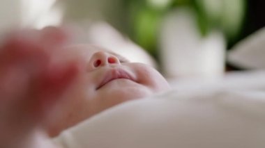 Oynayan ve ellerini ağzına koyan bir bebeğin yakın plan görüntüsü. Görüntüyü bulanıklaştırır ve sadece bebeklerin yüzlerine odaklanır. Yeni doğuş, annelik, bebeklik, bebek ürünleri kavramı..