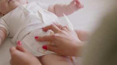 Görüntüyü yaklaştır. Yeni doğan bakım rutini. Annem bebek bezi değiştiriyor. Genç anne hassas ciltli bebeğe bakar. Narin ve kaliteli bebek bezleri ile bakım ve konfor