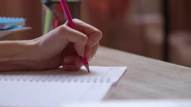 Kalemle not defterine not alan bir kadının yakın plan görüntüsü. İş kadını bir kağıt üzerinde bilgi topluyor. Ofis masası, esmer kız sol eliyle önemli notlar yazıyor.