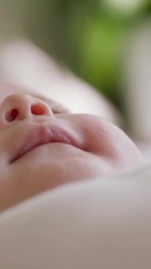 Oynayan ve ellerini ağzına koyan bir bebeğin yakın plan görüntüsü. Görüntüyü bulanıklaştırır ve sadece bebeklerin yüzlerine odaklanır. Yeni doğuş, annelik, bebeklik, bebek ürünleri kavramı..