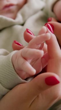 Bebeğin anne eliyle oynadığı yakın plan görüntü. Bebeğin annesinin kollarında otururken çevreyi keşfetmesi. Bebek ellerle tek başına oynuyor. Sessiz ve rahat ev ortamı