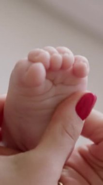 Bebek ayağına masaj yapan genç bir annenin ellerine yakın çekim. Evde yeni doğan bakımı rutini. Bebek anne tarafından dokunulduğunda ayak parmaklarını kendi başına yayar. Yeni doğan bakım ürünleri kavramı