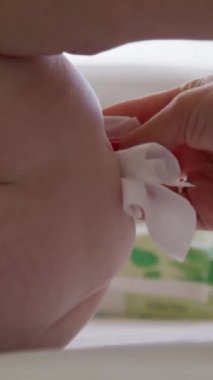 Görüntüyü yaklaştır. Yeni doğan bakım rutini. Bir anne, bebeğin poposunu peçeteyle okşar. Anne bezini değiştiriyor ve yumuşak bir peçeteyle bebeğin hassas cildini siliyor. Dikkat ve rahatlık