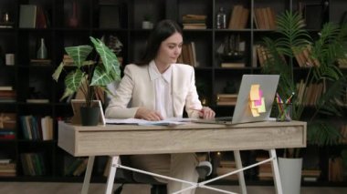 İş yerinde zarif kıyafetler giyen genç bir kadın çevrimiçi bir konferansa katılıyor ve konuşma becerilerini geliştiriyor. İşveren çevrimiçi bir foruma şirket adına katılır.