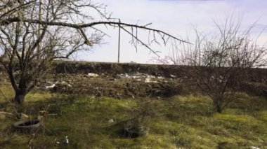 İnsanların attığı çöplerle dolu bir orman. Yeşil doğa alanı, plastik torbalar, şişeler, plastik çöpler. Yeşil alanda inşaat atığı yığını. Tepedeki yasadışı çöplük.