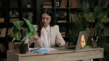 Bir öğrenci modern bir kütüphanede tezini hazırlıyor ve bir ofis masasında oturuyor. Öğrenci, uluslararası pazardaki büyük şirketlerin çeşitli istatistik ve grafiklerini analiz ediyor..
