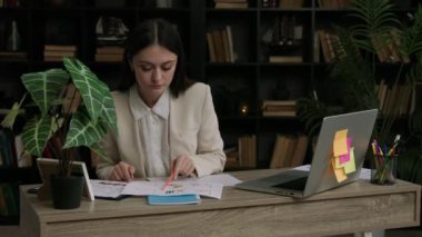 Klasik takım elbiseli öğrenci stajını bir pazarlama şirketinde yapıyor. Kadın öğrenci, uluslararası pazardaki büyük şirketlerin istatistik ve grafiklerini inceliyor..