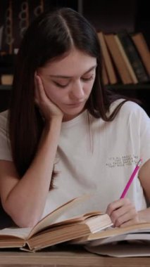 Çeşitli kaynaklardan çalışkan öğrenci çalışmaları. Genç kadın yoğun bir şekilde sınavlara, sınavlara ve üniversite projelerine hazırlanıyor. Öğrenci, proje, eğitim kavramı