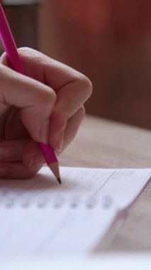 Kalemle not defterine not alan bir kadının yakın plan görüntüsü. İş kadını bir kağıt üzerinde bilgi topluyor. Ofis masası, esmer kız sol eliyle önemli notlar yazıyor.