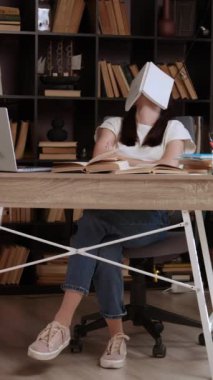 Modern bir kütüphanede, bir ofis masasında yüzünün üzerinde bir kitapla oturan yorgun kız öğrenci. Genç esmer, öğrendiği her şeyi okuyarak ve gözden geçirerek sınavlara hazırlanıyor..