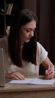 Esmer öğrenci iş arkadaşlarıyla bir grup projesi hazırlıyor. Genç kadın bilgisayardaki meslektaşlarıyla video görüşmesi yapıyor ve projeyi tartışıyor. Öğrenci not alıyor.