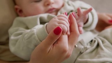 Yakından bakınca, bebek annesinin kollarında oturur ve elleriyle oynar. Anne bebeklerin ellerini sıkıca tutuyor ve onlara ilgi ve güvenlik sunuyor. Bebek sessizce oturur, rahatlar ve esner.