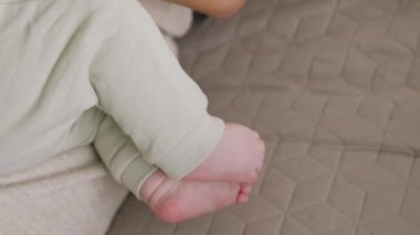 Anne kollarında oturup anne sütü yerken yeni doğmuş bebeklerin ayaklarına yakın çekim. Bebek yumuşak ve kadife tenli ayaklarıyla tek başına oynuyor. Sakin, sakin ve rahat bir ortam.