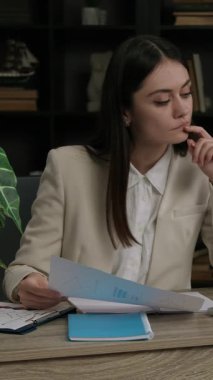 Konsantre iş kadını dizüstü bilgisayardaki ayrıntılı çizelgeyi gözden geçiriyor. Kadın ofis çalışanı gerekli verileri ilgili belge alanlarına aktarıyor