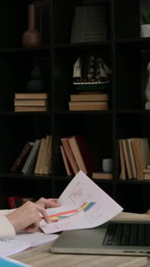 İş kadınının elinde ofisteki bilgisayar ekranında bilgileri kontrol eden belgeler var. Kadın girişimci finansal tabloları ve grafikleri analiz eder