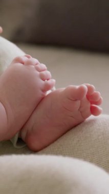 Bir çocuğun ayaklarının ve ayak parmaklarının yakın plan görüntüsü. Açık yeşil elbiseli annenin kollarında oturan bebek nazikçe ayaklarıyla oynar. Parlak, rahat bir ev gibi. Güzel annelik