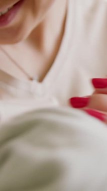 Genç bir annenin çocuğuyla oynaşıp küçük ellerini öperkenki görüntüsü. Çocuk annesine bakar, aktif olarak ellerini sallar. Bir çocuk için annelik bakımı kavramı