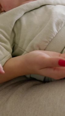 Yakından bakınca, bebek annesinin kollarında uzanıyor ve elleriyle oynuyor. Anne bebeğe dikkat ve güvenlik sağlar. Bebek sessizce oturur, rahatlar ve kollarını ve bacaklarını hareket ettirir..