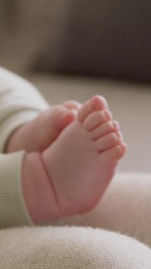 Güneşli bir günde annesinin kollarında oturan yeni doğmuş bir bebeğin ayaklarının yakın çekimi. Güneş ışınları bebek odasına nüfuz ediyor, küçük ayaklar sıcaklık ve güvenliği gösteriyor. Yeni doğan ayaklarını hareket ettirir.