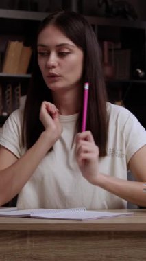 Genç esmer, bir ofis masasında oturmuş bilgisayar ve biniş kartı kullanarak yararlı bilgiler arıyor. Düşünceli öğrenci projesi için harika bir fikir buldu ve notlar alıyor.