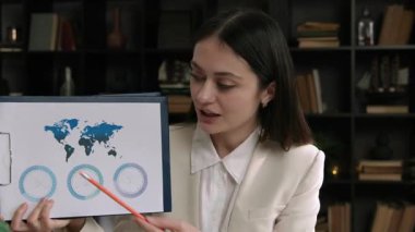 Gülümseyen esmer bir kadının portresi müşterilere çeşitli stratejiler sunuyor. Şirket büyümesini izlemek için çizelgeler. İş kadını, ortaklar ve yatırımcılarla çevrimiçi bir toplantıda tartışıyor