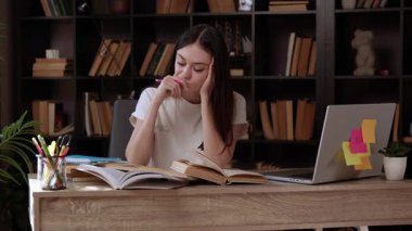 Kitaplardan, internetten ders çalışan ve notlar alan ciddi bir genç kadının portresi. Öğrenci, modern ve aydınlık bir odada, arkasında kitaplıklar olan bir proje hazırlıyor ve çalışıyor.