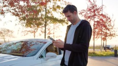 Yakışıklı adam hayallerindeki arabayı almayı başardığı için mutlu. Neşeli ve hevesli genç adam dans eder, ayağa fırlar ve satın alınan arabaya biner. Sonbahar günbatımında lüks beyaz bir araba.