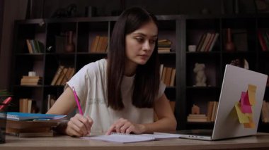 Genç öğretmen parlak ve modern bir ofiste çalışıyor ve öğrencilerle birlikte okul derslerine hazırlanıyor. Güzel esmer kadın internette ilginç bilgiler arıyor.