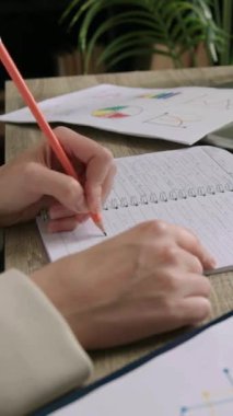 Kadın ofis çalışanı, iş yerindeki işleri dizüstü bilgisayarla planlayan kalemle not alıyor. Kadın çalışanlar ofiste planlama rutinine girişiyor