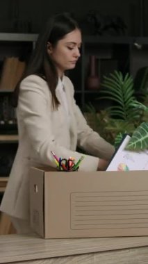 Kadın kutudaki şeyleri ev bitkisine yer açmak için yeniden düzenliyor. İş kadını resmi kıyafetler giyip yeni ofise taşınmak için kutu hazırlıyor.