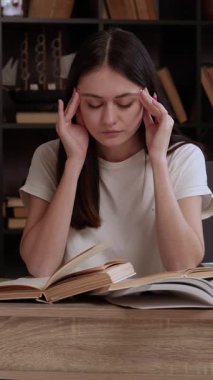 Modern ve güzel bir kütüphanedeki genç esmer öğrenci elleriyle başını ve şakaklarını tutuyor, aşırı çalışmaktan dolayı acı çekiyor. Güzel kız bir ofis masasında ders çalışıyor.