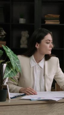 Kadın bilgisayardaki bir ofis masasında çalışıyor ve belgelerle notlar alıyor. İş kadını önemli ve karmaşık bir proje üzerinde çalışıyor ve yorgunluktan esniyor. Bağlılık ve sürekli çalışma