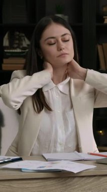 Bilgisayarın önünde çalışan bir kadının portresi. Klasik takım elbiseli bir kadın bilgisayarın önündeki sandalyede statik çalışmaktan dolayı acı çeken boyun egzersizleri yapıyor. Çalışmaya adanmışlık