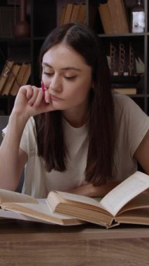 Konsantre ve düşünceli genç bir kadın ofis masasındaki birkaç açık kitaptan aynı anda okuyor. Esmer öğrenci modern bir ofiste okuyor ve üniversiteye hazırlanıyor.