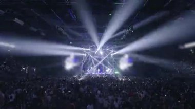 Kalabalık bir kalabalık canlı dans gösterileri ve sanatçılar izliyor. Aktif seyirciler büyük bir konser salonunda toplandı. Kalabalık hayranlar, dans eden insanlar, sahne ışıkları altında alkışlanan sanatçılar.