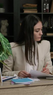 Profesyonel muhasebeci mali raporu gözden geçirir ve hesaplamaları düzeltir. Solak kadın kalemle düzeltme yapmak için belgeyi inceliyor