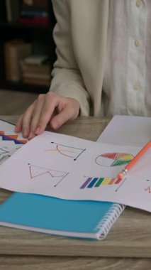 Ofis masasında dikkatlice ve titizlikle oturup birkaç belge, şema, şema, veri ve finansal rakamlarla analiz eden bir kadının ellerinin yakın plan görüntüsü. Hesap çekleri